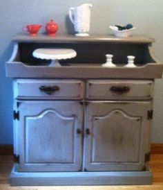 an old fashioned dresser with two dishes on it's top and one drawer open