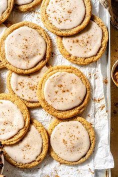 cookies with white icing and cinnamon sprinkles on a baking sheet lined with parchment paper