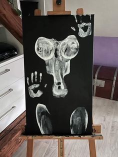 an easel with a black and white drawing of a hand and foot prints on it