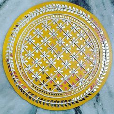 two yellow plates sitting on top of a marble counter next to each other, one with an intricate design