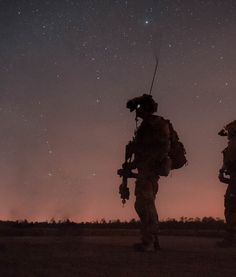 two soldiers are silhouetted against the night sky