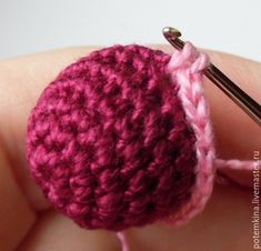 a crocheted object being held by someone's hand with a knitting needle