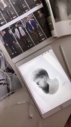 an open laptop computer sitting on top of a desk next to pictures and headphones