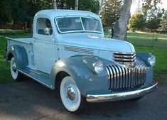 an old blue truck is parked on the street