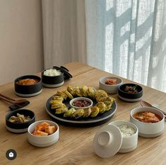 a wooden table topped with plates and bowls filled with different types of food on top of it