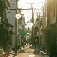 an alley way with people walking down it and power lines above the buildings in the background