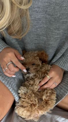 a woman in grey sweater holding a brown dog