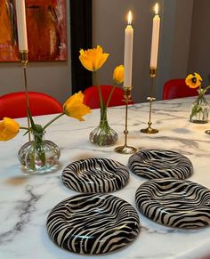 four zebra print coasters sitting on top of a table next to yellow flowers and candles