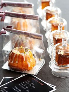 several small cakes in clear plastic bags on a table with black cards and tags around them