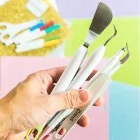 a person holding three different sized paintbrushes in their left hand and the other one has a pair of scissors on it