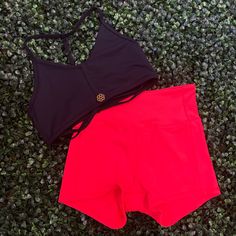 two women's swimsuits laying on the ground next to each other, one black and one red