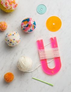 various craft supplies laid out on a white surface with yarn, buttons, and knitting needles