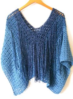 a blue crocheted shawl hanging on a wooden hanger