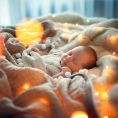 a baby is sleeping on a blanket with lights around it