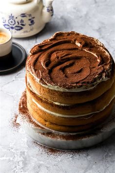 a stack of cake sitting on top of a plate next to a cup and saucer