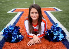 a cheerleader laying on the football field with her pom poms in hand