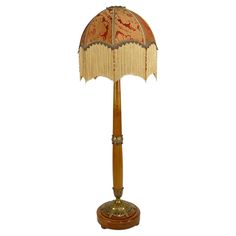 a lamp that is sitting on top of a wooden stand with a red and gold shade