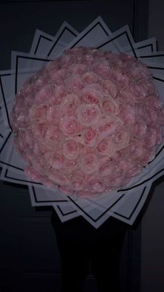 a bunch of pink roses in a white paper bowl on top of a black table