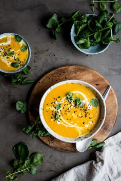 two bowls filled with carrot soup and garnished with herbs