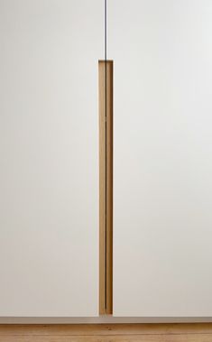 a wooden floor lamp on top of a hard wood floor next to a white wall