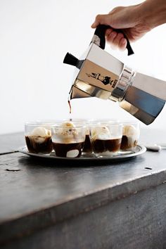 someone is pouring coffee into small cups on a plate with ice cream and chocolates