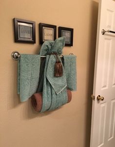 two towels are hanging on the wall in front of a door with three framed pictures