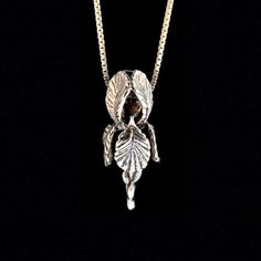 Our Iris Pendant is in full bloom. This beautiful Iris flaunts curvaceous frilled petals and the stem is detailed with unfolding leaves. It is cast in sterling silver and is 1 3/8" long and 1/2" across. A chain slips through side openings between the petals.  Bringing this design to fruition was fraught with technical challenges but I am thrilled with how it turned out. Creating an intricate design with an open center is difficult so the piece was cast in two parts and the halves soldered togeth Iris Pendant, Iris Necklace, Opalite Jewelry, Iris Jewelry, Movie Jewelry, Bohemian Jewels, Orchid Necklace, Magic Charms, Gift For Gardener