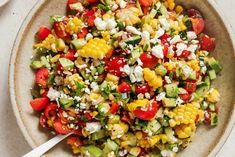 a bowl filled with corn and vegetables on top of a table