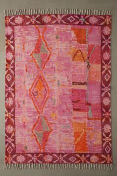 pink and orange rug with fringes hanging on the wall