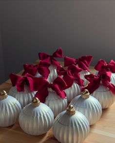 six white ornaments with red bows on them