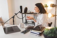 a woman sitting at a desk in front of a microphone talking to someone on her laptop