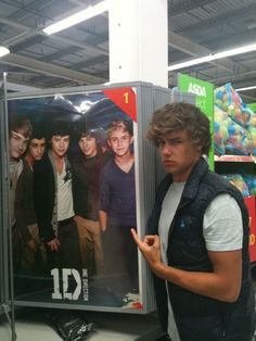 a young man standing in front of a movie poster