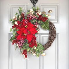 a wreath with poinsettis and greenery hangs on the front door