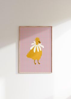 a yellow duck in a white and pink gingham dress is hanging on the wall