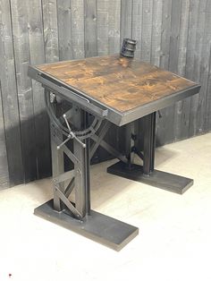 a wooden table sitting on top of a metal stand next to a wood wall and floor