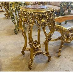 ornately decorated tables and chairs in an antique style store display case, with gold leaf detailing