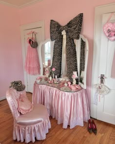 a pink and black room with leopard print on the wall, chair, mirror and dressing table