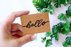 a person holding up a piece of paper with the word hello written on it in black ink