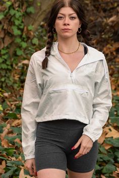 woman in state park bidwell park wearing biker shorts and upper park clothing's white windbreaker. model with two braids and red nails. cotton dark gray biker shorts, chico, california, butte county, athleisure, cropped windbreaker, quarter-zip windbreker Old Script, Cropped Windbreaker, Bomber Jacket, Athletic Jacket, Lifestyle, Clothes For Women, White, Clothes