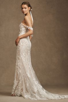 a woman in a wedding dress posing for the camera with her hand on her hip