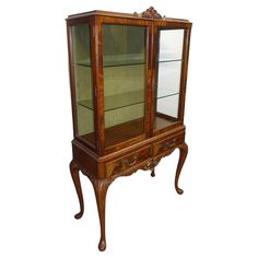 an antique wooden display cabinet with glass doors