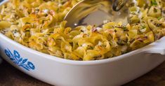 a white dish filled with macaroni and cheese on top of a wooden table