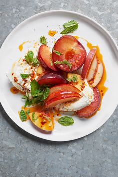 a white plate topped with sliced peaches and ice cream on top of a table