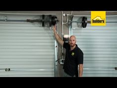 a man in black shirt standing next to a garage door with roller doors on it