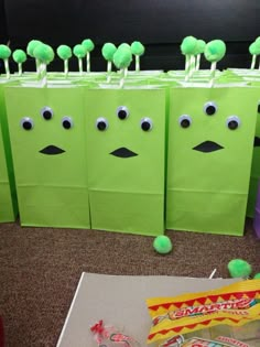 green paper bags with faces on them and candy sticks sticking out of the top one