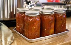 six jars of pickles sit on a tray