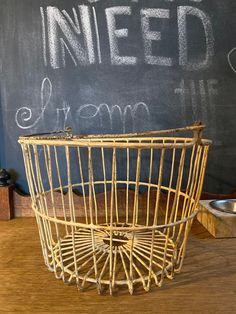 a basket sitting on top of a wooden table next to a chalkboard with writing on it