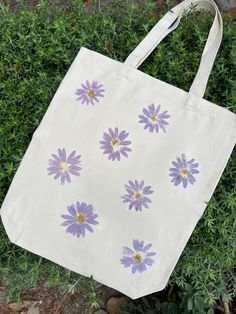 The Daisy Tote Bag is made witth real California daisies foraged in my neighborhood and hammered into canvas for the pigment to transfer. Makes a great gift! Can be done with any type of flower (if sourcing allows). Made in batches, each bag is unique, some flowers may not transfer as "perfectly" as shown here. Simple Bag Design Ideas, Tout Bag Ideas, Tote Bag Painting Ideas Flowers, Simple Tote Bag Design, Tote Bag Decoration, Painted Canvas Bags, Handpainted Tote Bags, Diy Gift For Bff, Sac Tote Bag