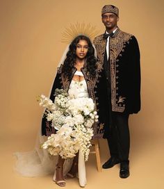 a bride and groom pose for a photo in front of a gold background with white flowers