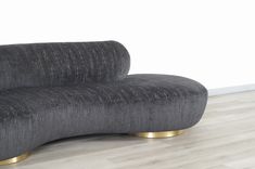 a black couch sitting on top of a hard wood floor next to a white wall